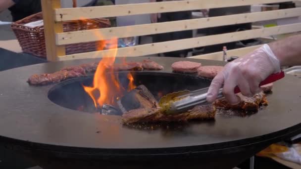 Mouvement lent : le chef grille des steaks de viande et des escalopes sur brasero à la flamme chaude — Video