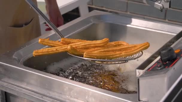 Slow motion: chef-kok kokende churros in kokende olie op de markt voor straatvoedsel: close up — Stockvideo