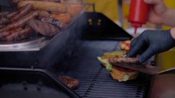 Slow motion: kock händer matlagning hamburgare på grill på gatumarknaden - närbild — Stockvideo