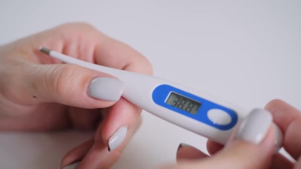 Nahaufnahme: Frau hält digitales medizinisches Thermometer mit hoher Temperatur — Stockvideo
