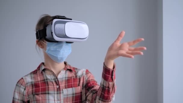 Молода жінка в медичній масці для обличчя та гарнітурі віртуальної реальності концепція VR — стокове відео
