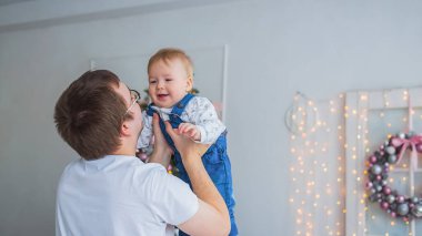 Genç baba, parlak beyaz odaya oğlunu kusuyor.