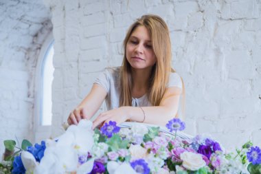 Çiçekçi, çiçekçide büyük bir çiçek sepeti yapıyor.