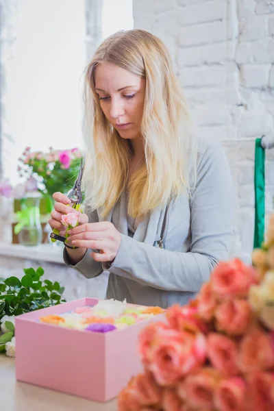 Professional florist making gift box with flowers at flower store