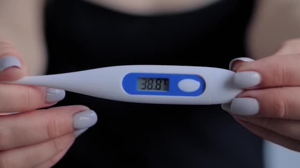 Nahaufnahme: Frau zeigt digitales medizinisches Thermometer mit hoher Temperatur — Stockvideo