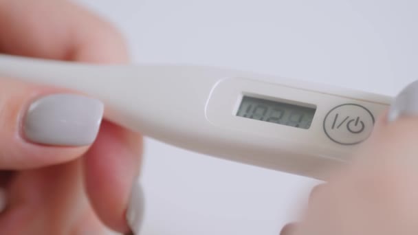 Крупный план: женщина показывает цифровой медицинский термометр с высокой температурой — стоковое видео