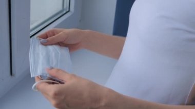 Ağır çekim: düşünceli kadın maske takıyor ve pencereden dışarı bakıyor.