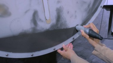 Mıknatıs sopalı kadın demir kum parçacıklarını kontrol ediyor