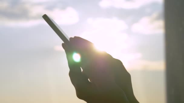 Mão da mulher usando smartphone contra a luz do sol, brilho da lente solar: vista lateral de perto — Vídeo de Stock