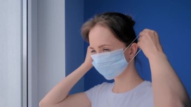 Yakın plan: medikal maske takan ve pencereden dışarı bakan düşünceli kadın