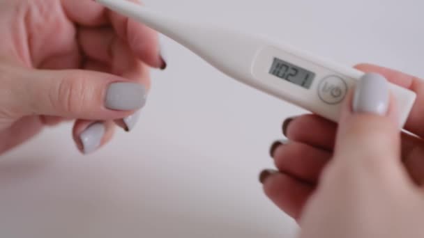 Κοντινό πλάνο: γυναίκα κρατώντας ψηφιακό ιατρικό θερμόμετρο με υψηλή θερμοκρασία — Αρχείο Βίντεο