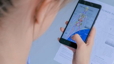 Artırılmış gerçeklik uygulaması olan akıllı telefon kullanan kadın: İnsan vücudunun 3 boyutlu modeli