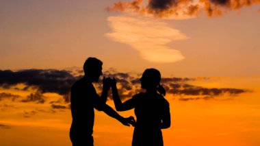 Romantik çift gün batımında dans ediyor.