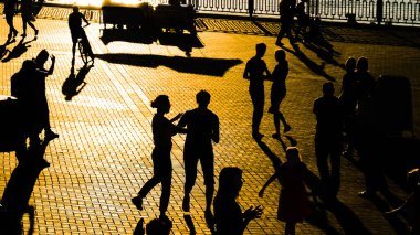 Birçok insan gün batımında şehir setinde dans ediyor.