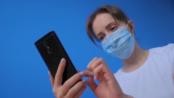 Portrét ženy v lékařské masce obličeje a pomocí smartphonu - zpomalení — Stock video