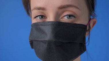 Kendini izole etme konsepti. Tıbbi yüz maskesi takan kadın, kameraya bakıyor.