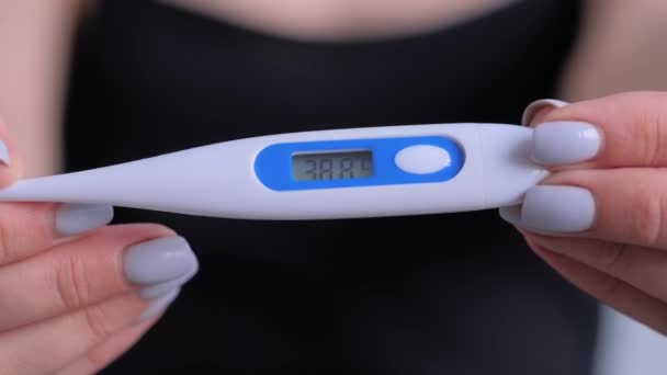 Nahaufnahme: Frau hält digitales medizinisches Thermometer mit hoher Temperatur — Stockvideo