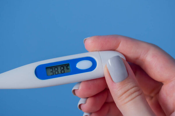 Woman hands holding white digital medical thermometer with high temperature - close up view, selective focus. Healthcare, measurement, disease, infection, coronavirus concept