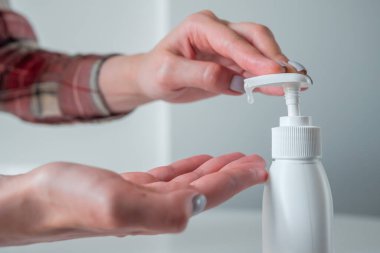 Kadın avuç içine antiseptik jel sıkıyor. Yan görüş kapalı.
