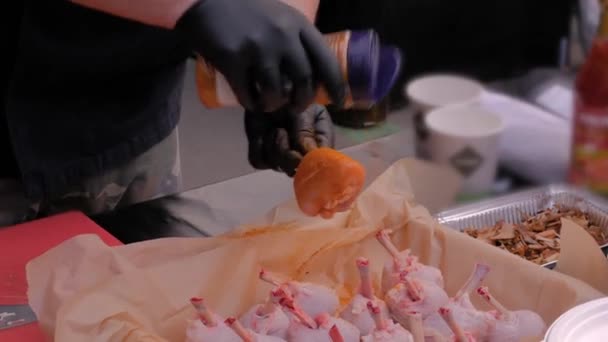 Kok bereidt kippenpoten met specerijen op street food festival - close-up view — Stockvideo
