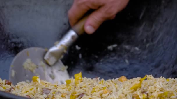 Slow motion: chef-kok kokend kussen in enorme ketel in de zomer buiten voedsel markt — Stockvideo