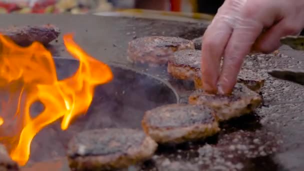 Movimento lento: Chef grelhar costeletas de carne para hambúrgueres no braseiro com chama quente — Vídeo de Stock