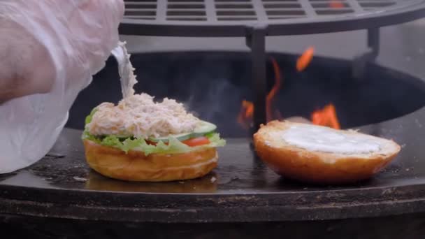 Slow motion: chef-kok bereidt visburgers op street food festival - close up — Stockvideo