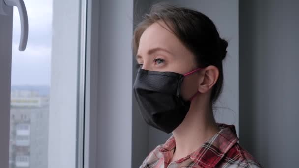 Movimento lento: mulher pensativa usando máscara facial médica e olhando pela janela — Vídeo de Stock