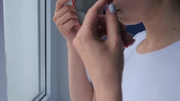Slow motion: dure vrouw die een zwart gezichtsmasker opzet en uit het raam kijkt — Stockvideo