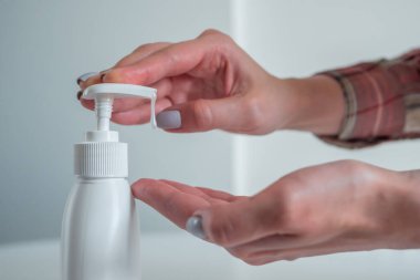 Kadın şeker kutusunu itiyor, avuç içine antiseptik jel sıkıyor. Yakın çekim.