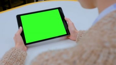 Evde yeşil ekranlı tablet bilgisayara bakan bir kadın