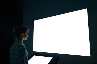 Woman looking at white empty large wall display - mockup image