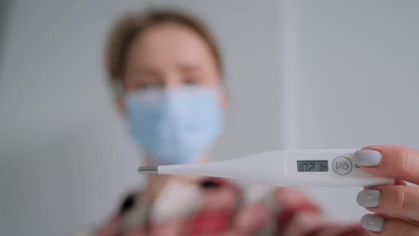 Slow motion: woman in medical face mask looking at medical thermometer at home — Stock Video