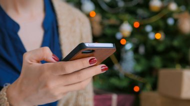 Evde akıllı telefon kullanan genç bir kadın.