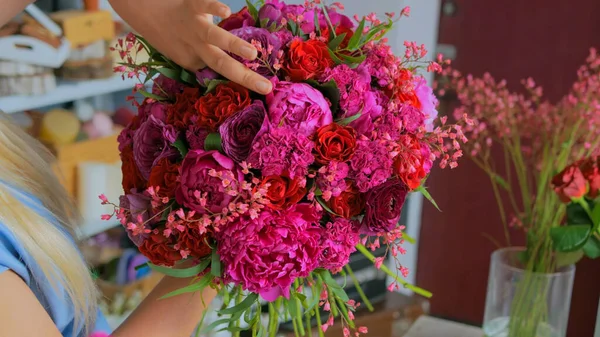 Professional florist making beautiful bouquet at flower store