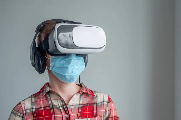 Young woman wearing medical face mask and virtual reality headset - VR concept