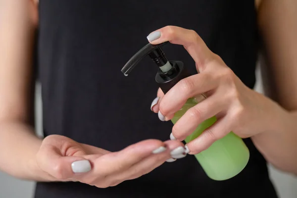 Woman squeezing out antiseptic gel on palm - close up front view