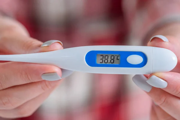 Woman showing medical thermometer with high body temperature at home - close up