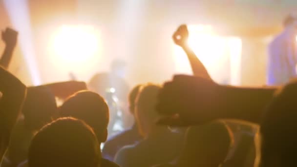 Super cámara lenta: siluetas de personas festejando en concierto frente al escenario — Vídeo de stock