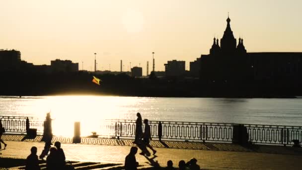 Siluetas de la gente caminando en el muelle de la ciudad al atardecer - cámara lenta — Vídeo de stock