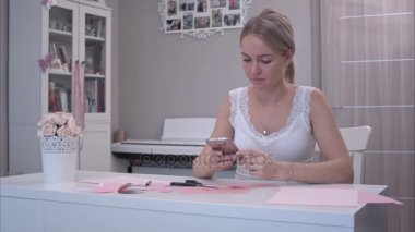 Telefonunu kağıt kelebekler kesmek süre kullanan genç kadın