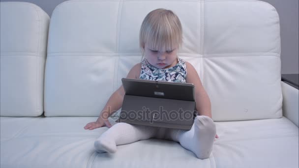 Серйозна дівчинка грає з планшетом — стокове відео