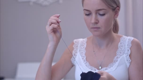 Молодая женщина перерезает нитку ножницами во время шитья — стоковое видео