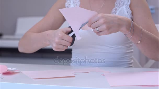 Молодая женщина вырезает бумажную бабочку — стоковое видео
