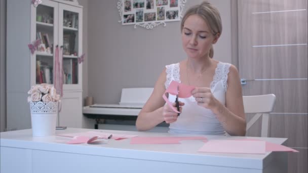 Женщина вырезает бабочку из розовой бумаги — стоковое видео