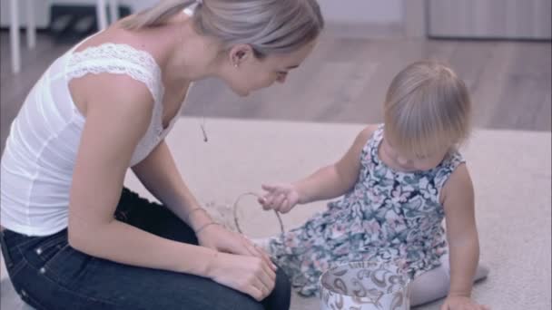 Щаслива молода мама і її маленька дочка досліджують коробку для ювелірних виробів, що сидить на килимі — стокове відео