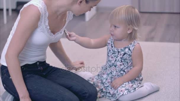 Мать и ее маленький ребенок пробуют броши друг на друге — стоковое видео