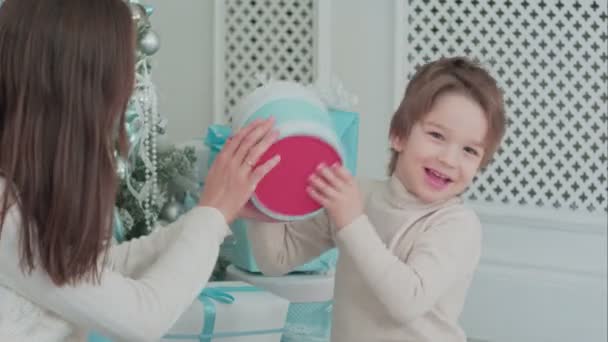 Mor och glad son kontrollera gåvor som sitter nära julgranen — Stockvideo