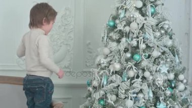 Küçük çocuk Noel ağacı üzerinde önemsiz şey kendi yansıması, dilini yapışkanlık dışarı