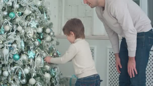 Padre e hijo decorando el árbol de Navidad con adornos en la sala de estar — Vídeos de Stock